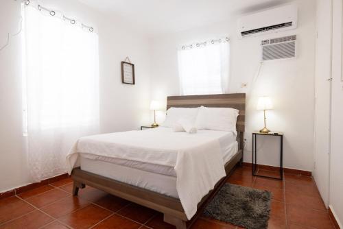 a bedroom with a bed with white sheets and two lamps at R&V Combate Beach House 1 with Pool in Cabo Rojo