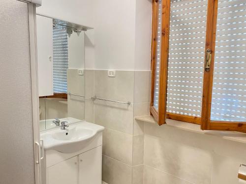 Baño blanco con lavabo y espejo en Orlandi Sun casa 2, en Sarnano