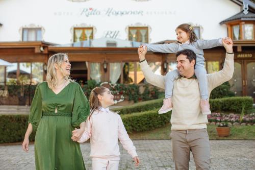 a family of three walking in front of a house at Hotel Ritta Höppner in Gramado