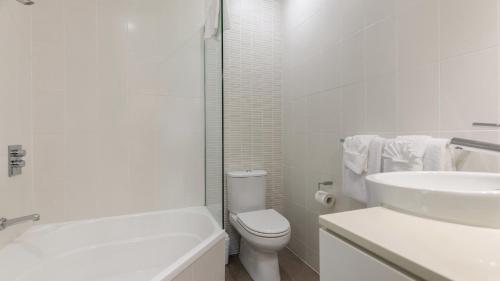 een witte badkamer met een toilet en een wastafel bij Watermark Villa Port Douglas in Port Douglas