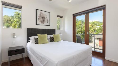 een witte slaapkamer met een groot bed en ramen bij Watermark Villa Port Douglas in Port Douglas