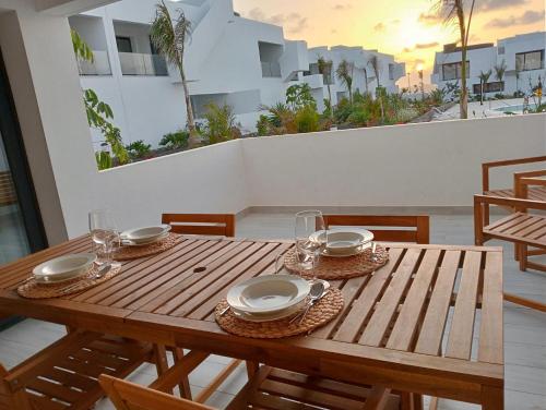 una mesa de madera con platos y vasos en el balcón en Aulaga en Villaverde