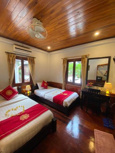 a bedroom with two beds and a mirror and a desk at Golden Lotus Boutique Hotel in Luang Prabang