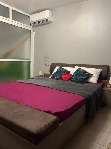 1 cama con sábanas rosas y almohadas en una habitación en Appart charmant - Lumineux en Les Abymes