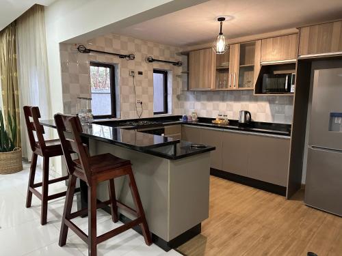 a kitchen with a island with two bar stools at Kaya Apartments in Lusaka