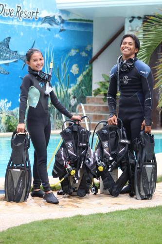 two women in wet suits standing next to a pool at Love's Beach & Dive Resort in Moalboal