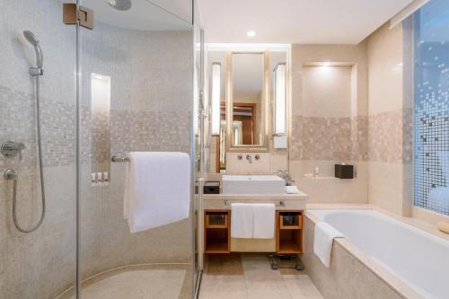 a bathroom with a tub and a sink and a shower at Swissôtel Grand Shanghai - Stroll down West Nanjing Road and soak in downtown Shanghai vibrancy in Shanghai