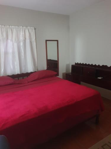 1 dormitorio con cama roja y espejo en Campbell's living accommodations. en Gwa Kay
