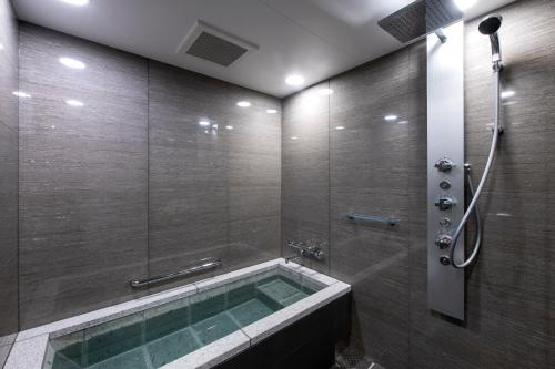 a bathroom with a bath tub with a shower at Hotel GrandBach Sendai in Sendai