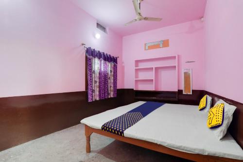 a bedroom with a bed and a pink wall at SPOT ON New Modern Guest House in Varanasi