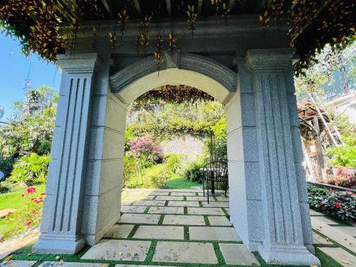 a stone archway with a bench in a garden at Hotel Hoa Nắng in Bao Loc