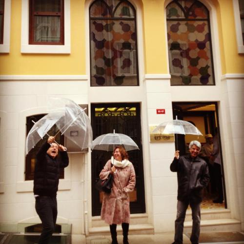 drie mensen met transparante paraplu's voor een gebouw bij Ottopera Hotel in Istanbul