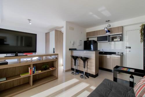 a living room with a television and a kitchen at Sunset Studio - GRU in Guarulhos