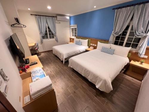 a hotel room with two beds and a television at 陽光小灣旅店 in Kenting