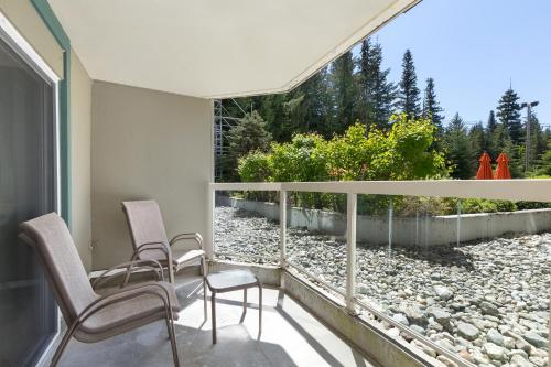 a balcony with two chairs and a large window at The Woodrun Lodge by Whiski Jack in Whistler