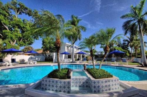 a swimming pool with palm trees and blue umbrellas at Gulfside Resort Unit 4 in St. Pete Beach
