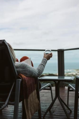 a woman sitting in a chair looking at her cell phone at Point of View Villas in Apollo Bay