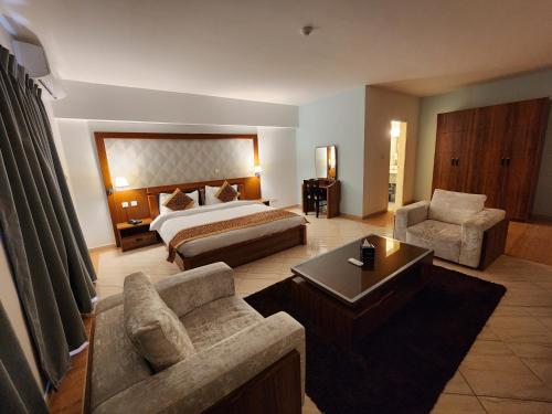 a hotel room with a bed and a couch and chair at Aquavista Hotel & Suites in Aqaba