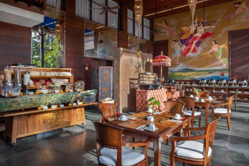 a restaurant with wooden tables and chairs and a large painting at The Alantara Sanur in Sanur