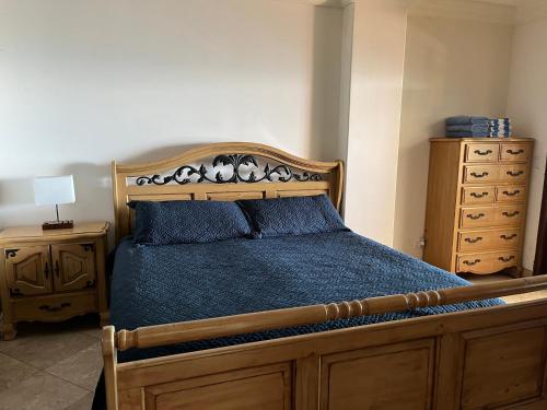 1 dormitorio con cama de madera y vestidor en Oceanview Condo Resort. Las Olas Grand Rosarito, en Divisadero