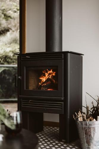 a black stove with a fire in a room at Point of View Villas in Apollo Bay