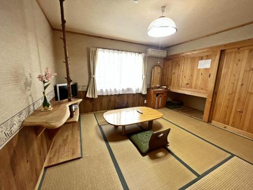 a room with a table and a desk and a window at Sendaiya in Hida