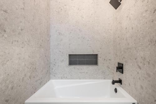 a white bath tub in a white tiled bathroom at FREE PARKING PRIME LOCATION NEW MODERN CONDO in Brossard