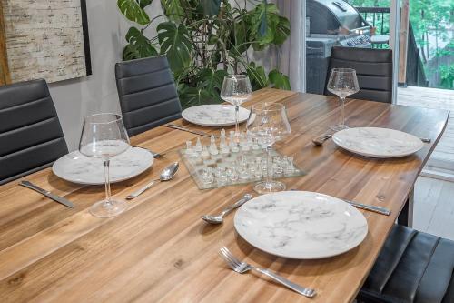 a wooden table with plates and wine glasses on it at FREE PARKING PRIME LOCATION NEW MODERN CONDO in Brossard