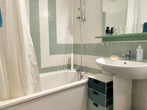 La salle de bains est pourvue d'un lavabo et d'une baignoire avec lavabo. dans l'établissement Appartement avec Piscine et Terrasse Proche Commerces - FR-1-748-15, à Canet