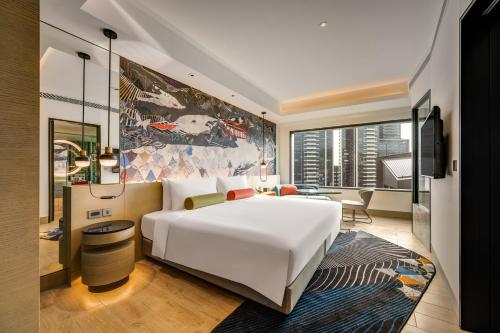 a bedroom with a large white bed and a living room at Hotel Indigo Taipei North by IHG in Taipei