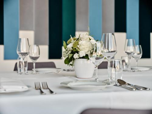 a table with a vase of flowers and wine glasses at Holiday Inn Gdansk - City Centre by IHG in Gdańsk