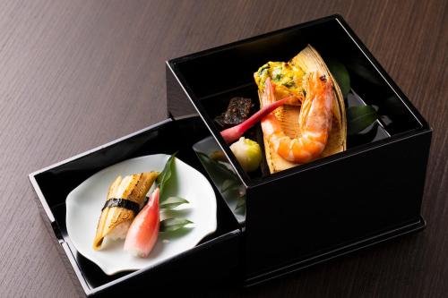 een doos met een bord eten op een tafel bij 料理の宿　伊豆の花 in Ito