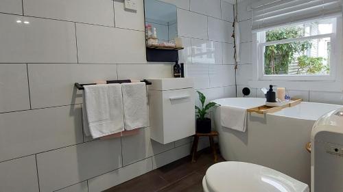 a white bathroom with a sink and a toilet at The Artists Cottage - absolute waterfront in Strahan