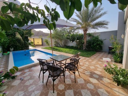 a patio with a table and chairs next to a swimming pool at Valley Villa in Jeddah