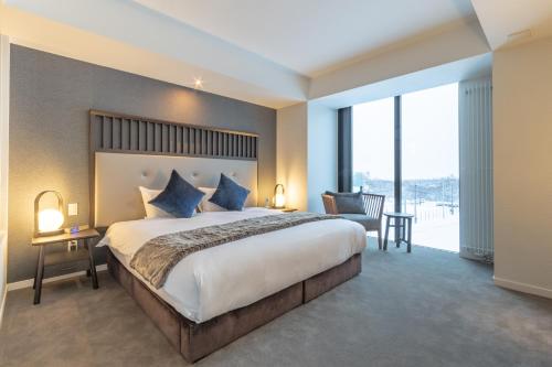 a bedroom with a large bed and a large window at The Vale Niseko in Kutchan