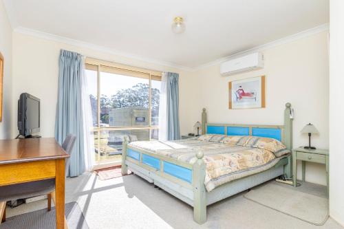 a bedroom with a bed and a desk and a window at Holiday on the Water in Sussex inlet