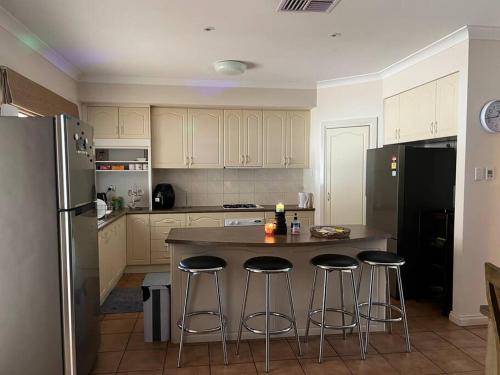 a kitchen with a island with bar stools and a refrigerator at Private self check in home in Alice Springs