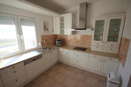 eine große Küche mit weißen Schränken und einem Waschbecken in der Unterkunft Apartment Maris with nice sea view in Ljubač
