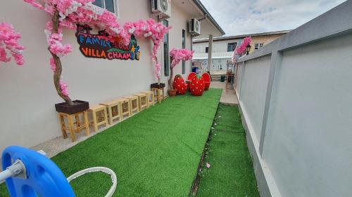 a walkway with pink flowers and trees in a building at Family POOL VILLA CHAAM in Cha Am