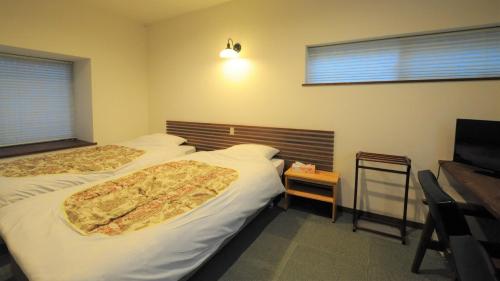 a hotel room with two beds and a television at Yourou Onsen Honkan in Onomichi