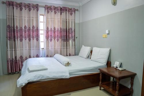 sypialnia z łóżkiem i oknem z zasłonami w obiekcie Empire House, Phnom Penh w mieście Phnom Penh