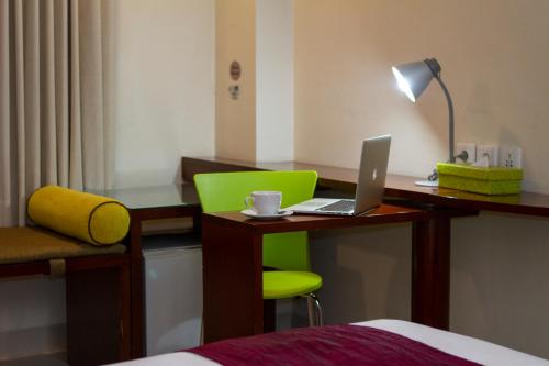 a room with a desk with a laptop and a chair at PrimeBiz Hotel Kuta in Kuta