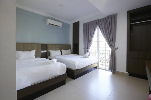 a hotel room with two beds and a window at Beryll Inn Cyberjaya Hotel in Cyberjaya