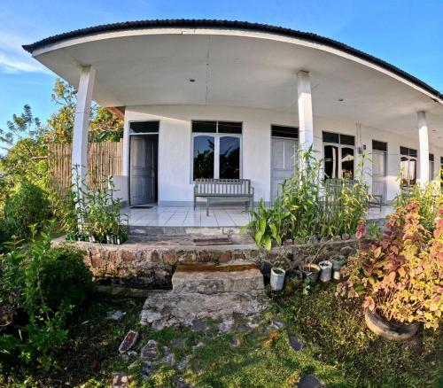 una casa blanca con porche y algunas plantas en Hidayah homestay, en Kelimutu