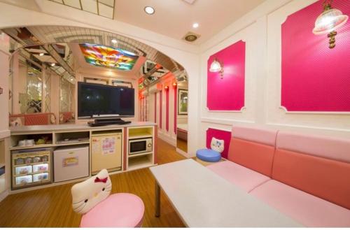 a living room with pink furniture and a tv at ホテル　アイネ　香芝店 in Kashiba