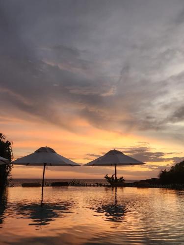 two umbrellas sitting in the water on a beach at Belika Beach in Hiriketiya