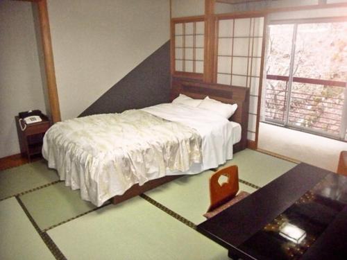 a bedroom with a bed and a table and a window at Yumura Onsen Tomiya - Vacation STAY 81718v in Yumura