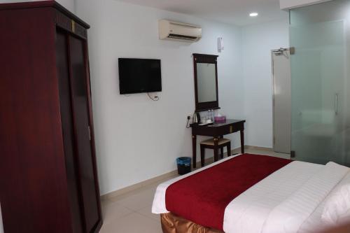 um quarto com uma cama e uma televisão na parede em Hotel AL Amin em Kuala Lumpur
