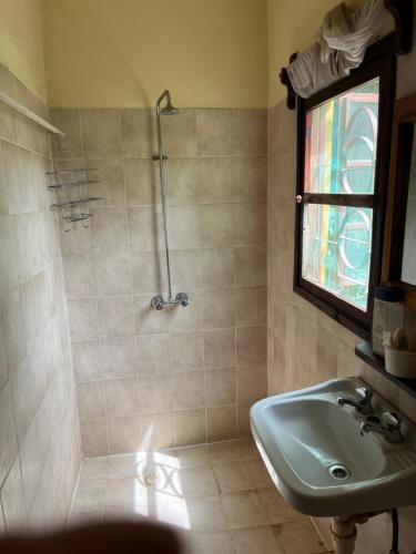 a bathroom with a sink and a shower with a window at Boli Boli Guesthouse in Sere Kunda