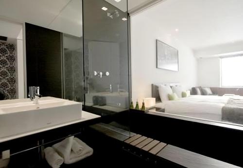 a bathroom with a sink and a bed and a mirror at The Vale Niseko in Kutchan
